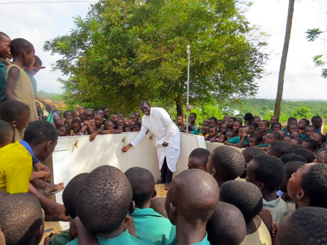 Father Anthony at water project with kids.
